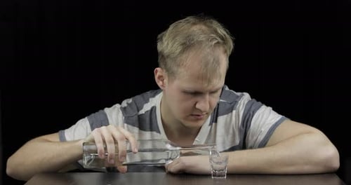 Depressed Man Drinking Vodka Alone in a Dark Room. Concept of Alcoholism
