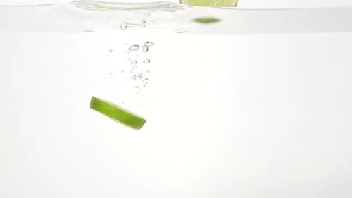 Lime Slices Falling into Water with Bubbles