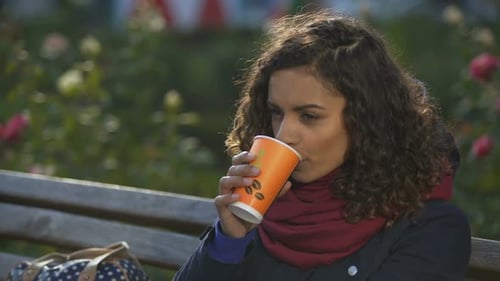 Woman Drinking Coffee in the Park on Bench