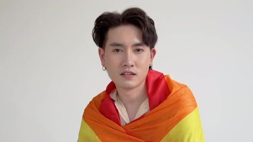 Young Adult Smiles with Rainbow Pride Flag Indoors