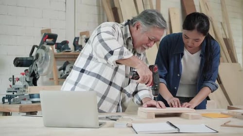 Man Drilling Wood as Woman Watches