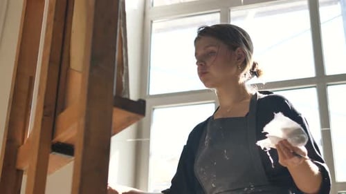 Artist in Black Shirt Draws Picture with Spatula Near Window