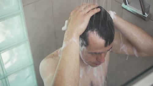 Young Man Washing Hair in Bathroom Shower