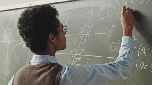 Young Adult Writing Equations on Chalkboard