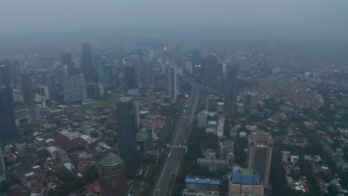 Aerial Wide Slow Shot of Multi Lane Highway Passing Through Busy Modern City Center with Skyscrapers