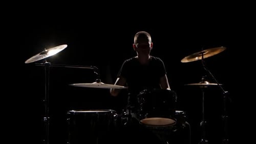 Musiker spielt professionell gute Musik am Schlagzeug mit Sticks. Schwarzer Hintergrund. Silhouette