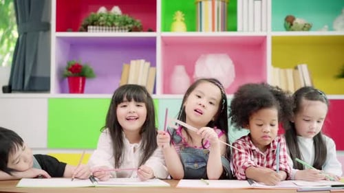 Multi-ethnic young boys and girls happy funny study and play painting on paper at elementary school.