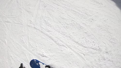 POV of a snowboarder snowboarding downhill at a ski resort.