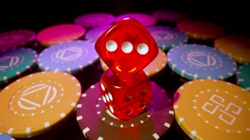 Red Dice Lying on a Pile of Casino Chips Spinning on a Black Background
