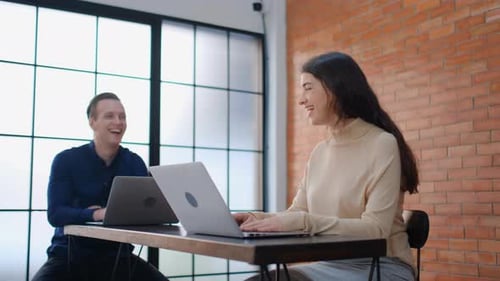 Man and woman use each laptop and sit on different side of table with concept of social distance