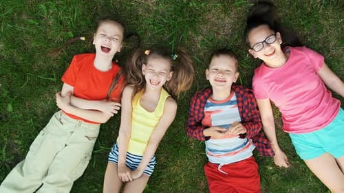 Smiling Children Relaxing on Green Grass Aerial View