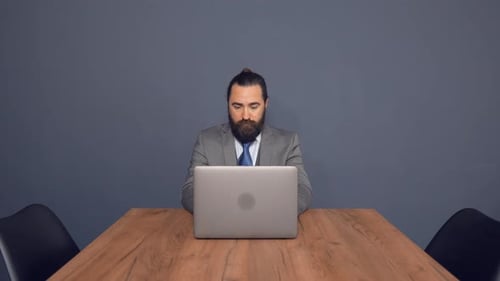 Bearded Businessman Is Working On Laptop Sitting at Office Desk