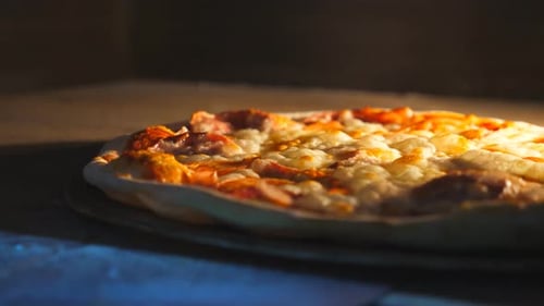 Young Cook Taking Out Tasty Pepperoni Pizza From Oven with a Shovel at Cuisine