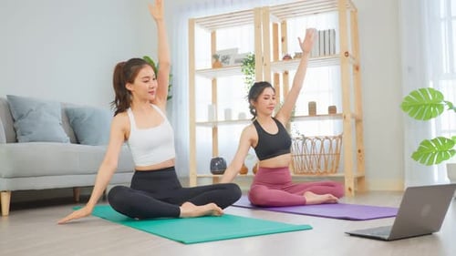 Amiga asiática activa haciendo ejercicios de yoga y pilates juntos en casa.