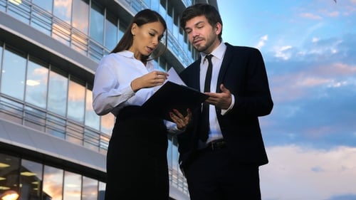 Young business people talking and viewing documents outdoors.