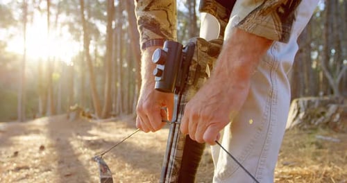 Homme ajustant son arc à poulies dans la forêt