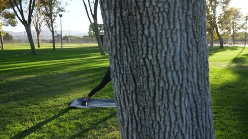 A healthy young woman stretching her legs before a fitness workout in the park at sunset SLOW MOTION