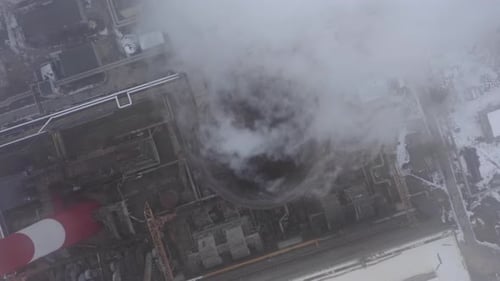 Smoking Factory Chimney Against the Background of Big Industrial City Covered with Snow