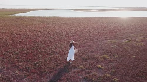 Chica con un vestido blanco caminando por la orilla