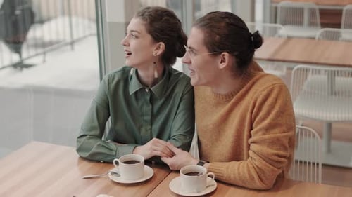Man and Woman Laughing while Sitting in Cafe