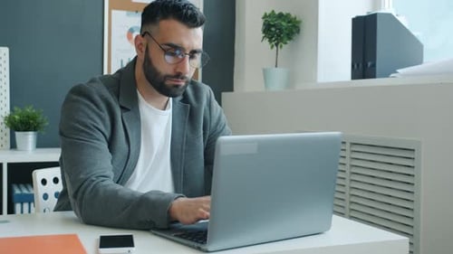 Empresario infeliz trabajando con una computadora portátil, luego golpeando la mesa con los puños y saliendo de la oficina