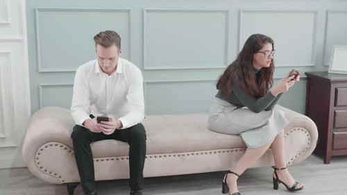Man and Woman Sitting on Chaise Lounge Using Phones