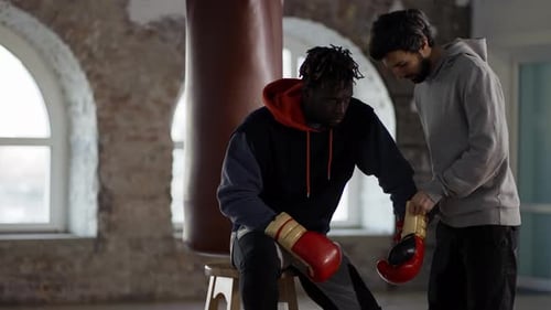 Man Lacing Boxing Glove for Athlete in Gym