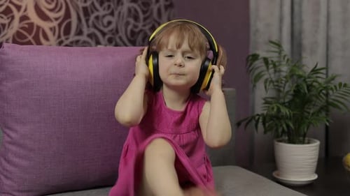 Little Girl Enjoying Music on Headphones Indoors