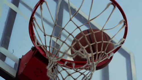 Unbekannte Person wirft Ball in Korb auf Sportspielplatz im Freien