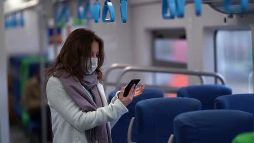 Woman Wearing Mask Uses Phone on Train