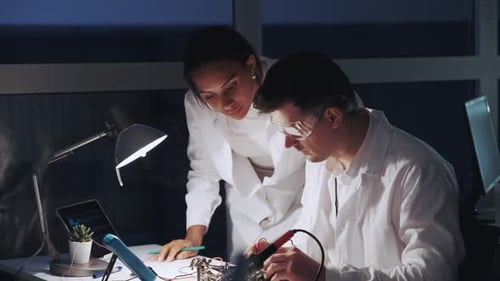 Dos ingenieros electrónicos de raza mixta que trabajan con multímetros, probador y otros dispositivos Electrónico
