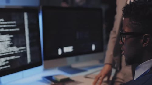 Man and Woman Collaborating on Computer Code at Night