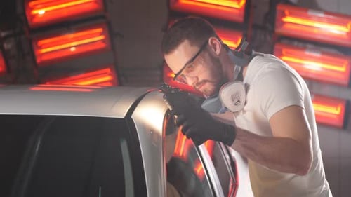 Man Repairs Car with Tool in Auto Body Shop