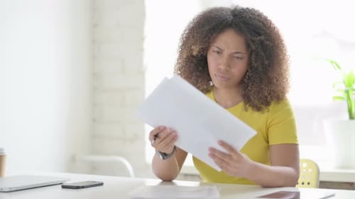 African Woman Upset while Reading Documents in Office