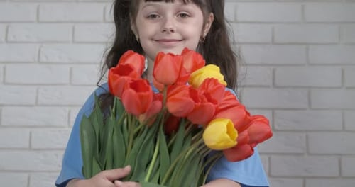 Smiling Child Holds a Tulip Bouquet