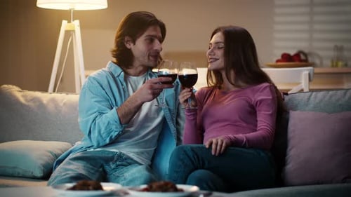 Young Happy Man Saying Love Toast to His Lovely Girlfriend Clinking Wine Glasses and Drinking