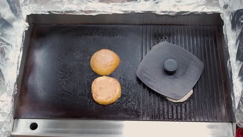 Burger Buns Heating Up on Professional Grill in Industrial Kitchen