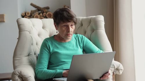 Senior Woman Using Laptop in Armchair at Home
