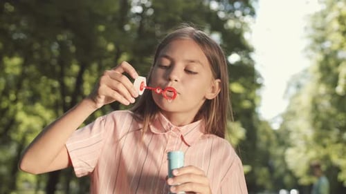 Girl Blowing Bubbles in Sunny Park Setting