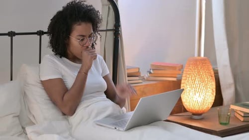 Woman Coughing While Working on Laptop in Bed