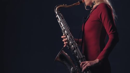 Elegant Woman Plays Jazz Saxophone in Dark Studio