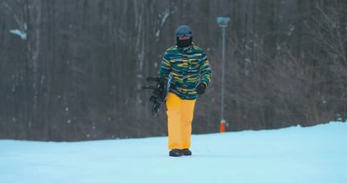 Snowboarder Walking on Snow Covered Hill