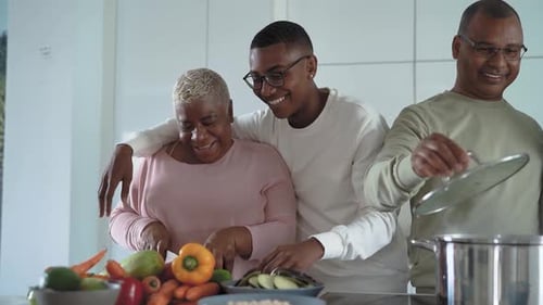 Happy African family having fun in modern kitchen preparing food recipe with fresh vegetables
