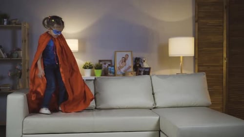 Girl Jumps on Sofa with Cape and Mask