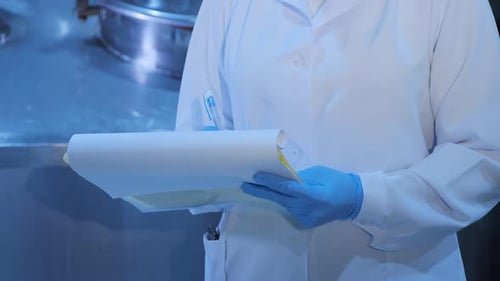 Inspektor in Handschuhen und Maske schreibt in Papieren in der Nähe von riesigen