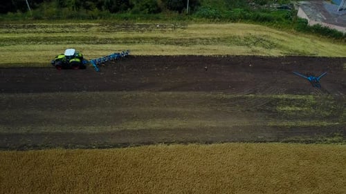 Plow Attached to a Tractor on a Field