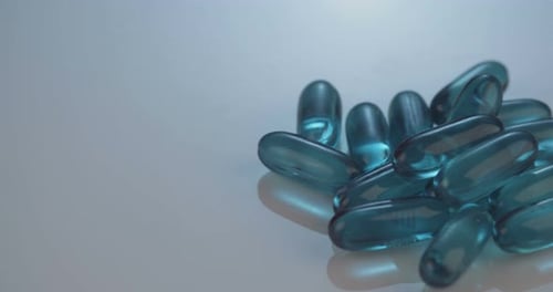 Turquoise Gel Capsules Gathered on Reflective Surface