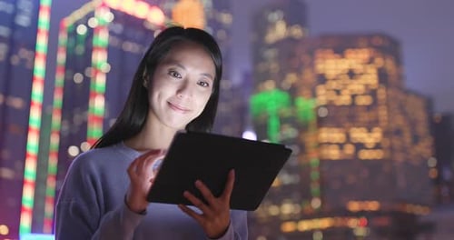 Woman Using Tablet in City at Night