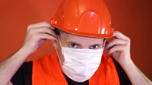 Construction Worker Puts on a White Face Mask