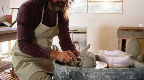 Male Potter Shaping Clay on Wheel in Studio